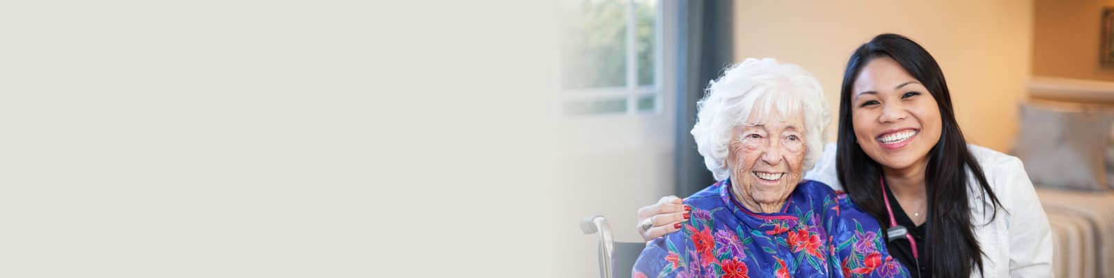 A resident in a wheelchair sitting next to a smiling nurse at the Western Slope Health facility