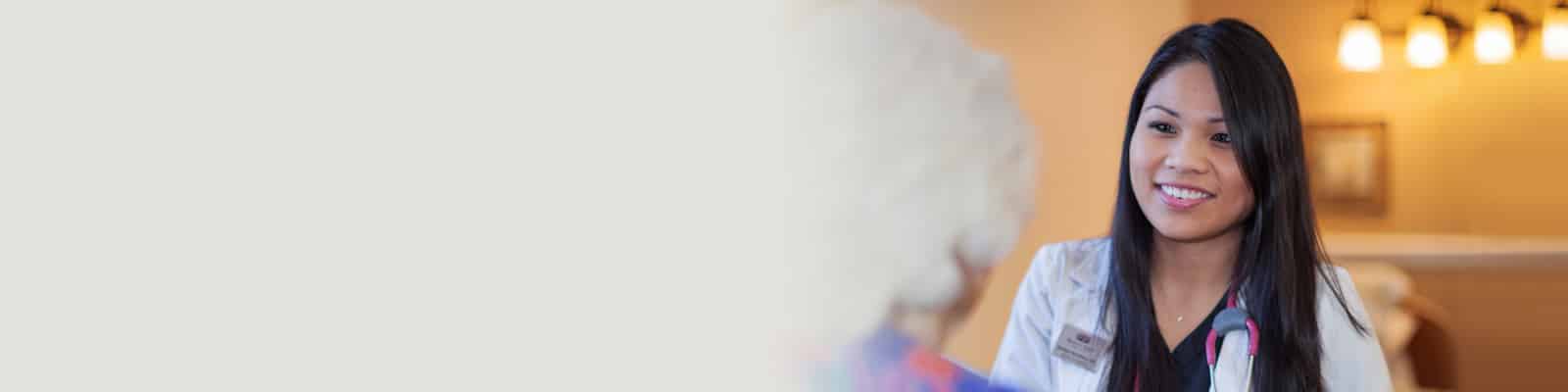 A resident in a wheelchair sitting next to a smiling nurse at the Western Slope Health facility