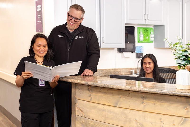 Nurses reading binder at front desk of Western Slope