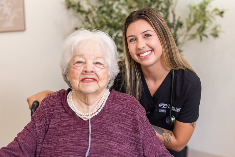 Smiling nurse posing with patient wearing oxygen device