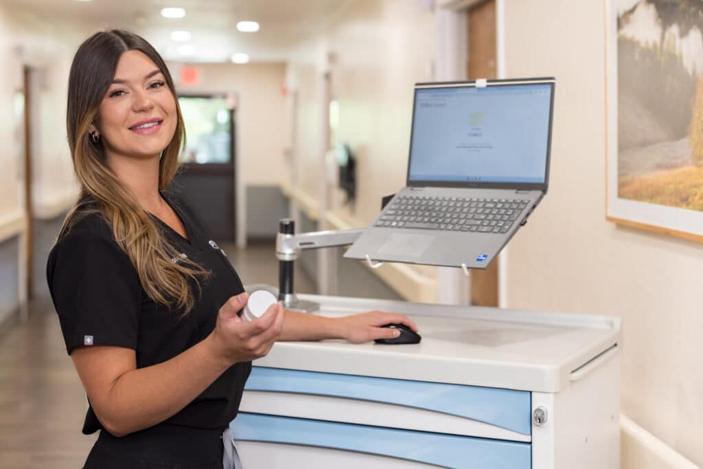 Nurse holding medicine bottle while looking at laptop